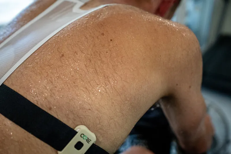Czujnik CORE na pasie piersiowym spoconego kolarza podczas treningu w cieple